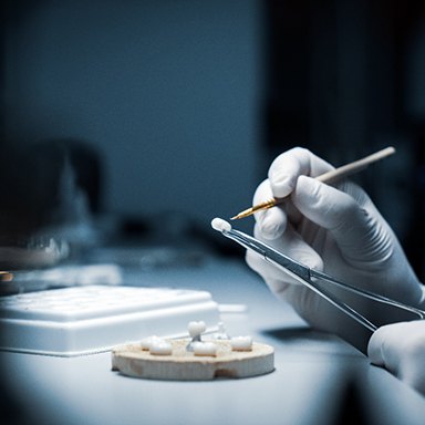 A lab technician processing a dental crown