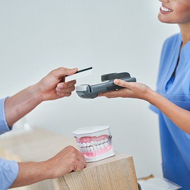 A man using a credit card to pay the cost of dental crowns
