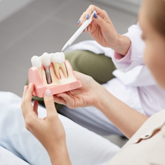 Dentist and dental patient looking at dental implant model