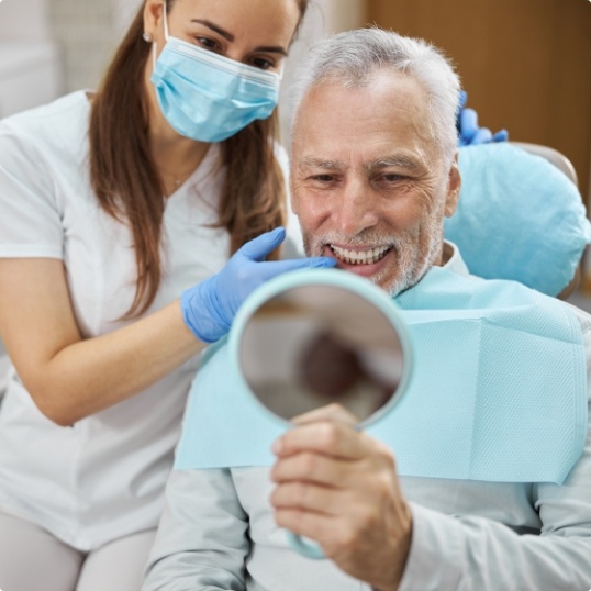 Man looking at smile after dental implant tooth replacement