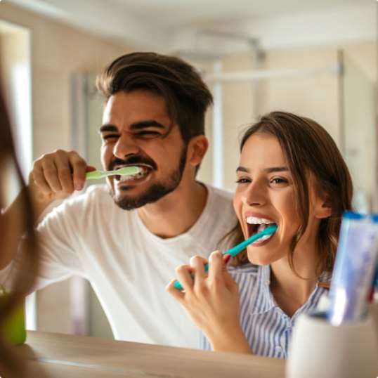 Man and woman brushing teeth to prevent dental emergencies