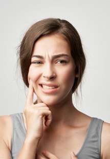 a woman touching her cheek due to tooth pain