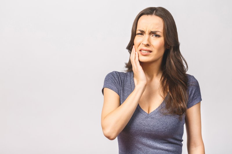 A grimacing woman holding her cheek