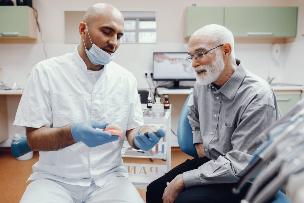 A dentist showing some dentures to his patient